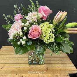 Pink roses and lilies arranged in a square glass vase