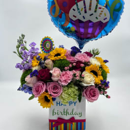 Birthday balloon above a colorful flower arrangement in a gift box