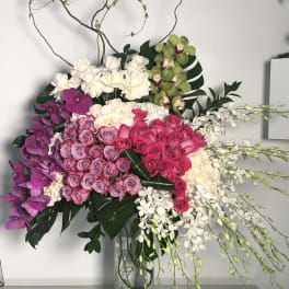 Large bouquet of pink, purple, and white flowers in a glass vase