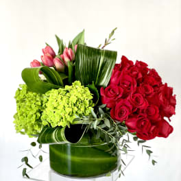 Red roses and pink tulips with green hydrangeas in a glass vase