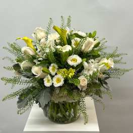 White and yellow floral arrangement in a glass vase