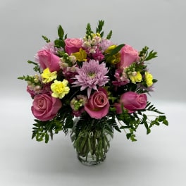 Pink and yellow mixed flower bouquet in a clear glass vase