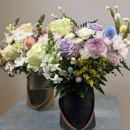 Pastel floral arrangement in a black vase with decorative eggs