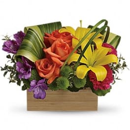 Orange roses and yellow lilies in a wooden box with purple flowers