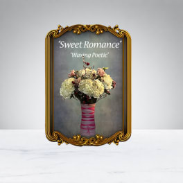 Bouquet of pale flowers in a pink-wrapped vase inside an ornate gold frame