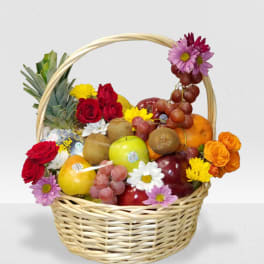 Wicker basket filled with assorted fresh fruit and colorful mixed flowers