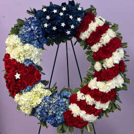 Circular floral wreath in red, white, and blue with star accents on a stand