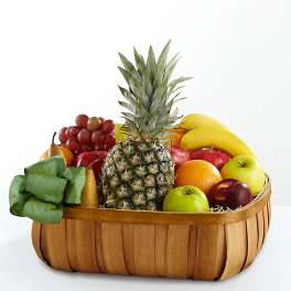 Fruit basket with pineapple, bananas, grapes, apples, and pears in a wooden basket