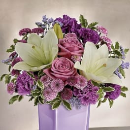 Purple and white floral arrangement in a lavender vase