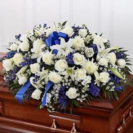 White and blue funeral spray on a casket with a blue ribbon