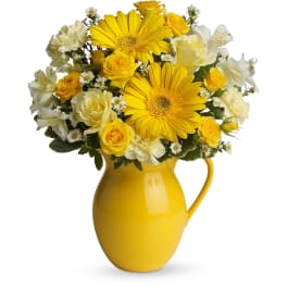 Yellow and white mixed flower arrangement in a bright yellow ceramic pitcher