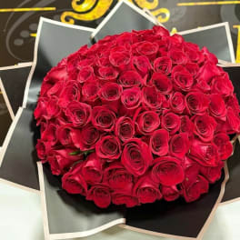 Round bouquet of red roses wrapped in black paper
