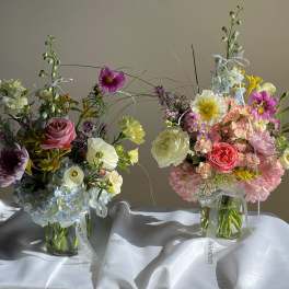 Two colorful flower arrangements in glass vases on a white cloth