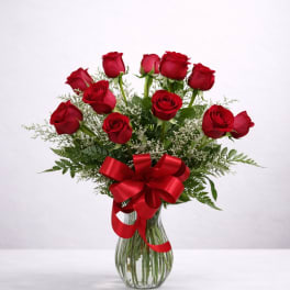 Red roses in a glass vase with a red ribbon bow