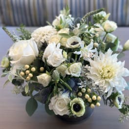 White floral arrangement in a black vase with roses and dahlias