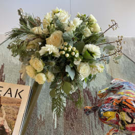 Cream and white floral bouquet with pine branches and berries in a vase