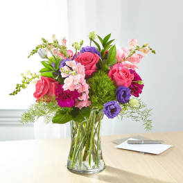 Mixed pink, purple, and white flowers in a clear glass vase