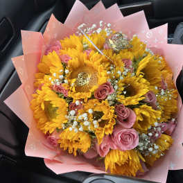 Bouquet of yellow sunflowers and pink roses wrapped in pink paper