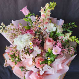 Pink and white mixed bouquet with roses and snapdragons in pink wrap