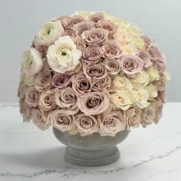 Round bouquet of pale pink and cream roses in a gray pedestal vase