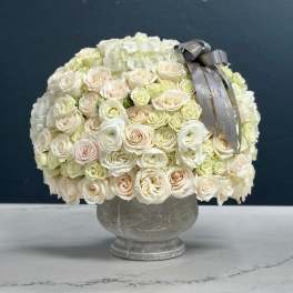 Cream rose bouquet in a gray vase with a silver ribbon