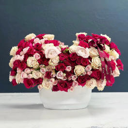 Large arrangement of pink, cream, and red roses in a white container