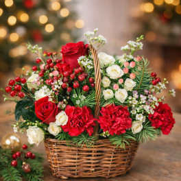 Basket arrangement of red and white roses with berries and greenery
