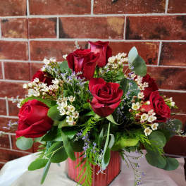 Red roses arranged in a glass vase with white filler flowers