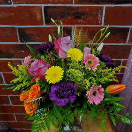 Mixed bouquet of roses, gerbera daisies, and carnations in a glass vase