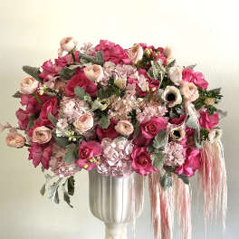 Pink floral arrangement in a white pedestal vase