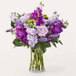 Purple and lavender bouquet with roses in a clear glass vase