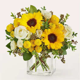 Yellow sunflowers and white roses in a clear glass vase