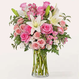Pink roses and white lilies arranged in a clear glass vase