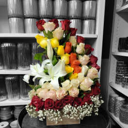 Tall bouquet of red, yellow, white, and peach roses with white lilies