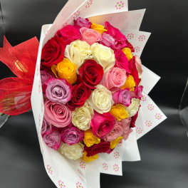Bouquet of multicolored roses wrapped in white paper with a red ribbon
