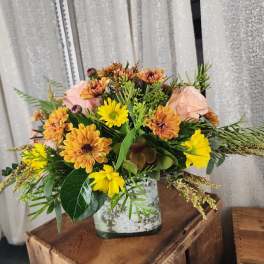 Mixed bouquet of yellow and peach flowers in a white vase