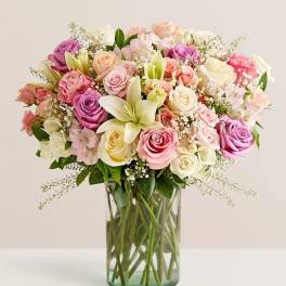 Mixed pastel bouquet of roses and lilies in a clear glass vase