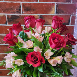 Red roses and pale pink alstroemeria in a glass vase