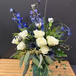 White roses and blue flowers in a green glass vase
