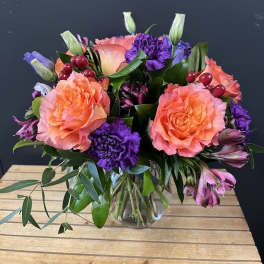Bouquet of orange roses and purple carnations in a glass vase
