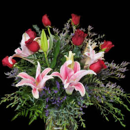 Pink lilies and red roses arranged in a glass vase