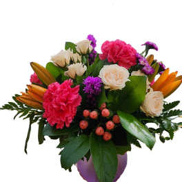 Low arrangement of pink carnations, cream roses, orange lilies and purple flowers in a round lavender vase