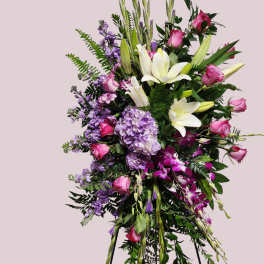 Tall standing floral spray with white lilies, pink roses, and purple blooms