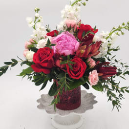 Bouquet of red and pink roses with white blooms in a glittery vase