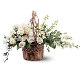 White roses in a wicker basket with trailing greenery