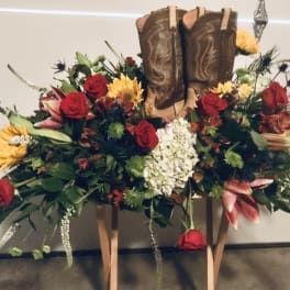 Cowboy boots surrounded by a floral arrangement of roses and lilies