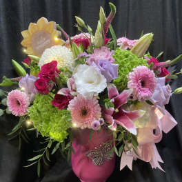 Pink and white mixed bouquet in a magenta vase with a sunflower sign