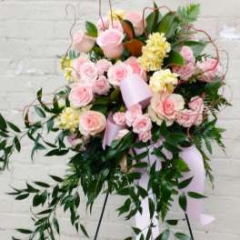 Pink rose and yellow flower standing spray with trailing greenery and ribbon