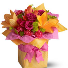 Bright bouquet of pink roses and orange lilies in a wrapped gift box