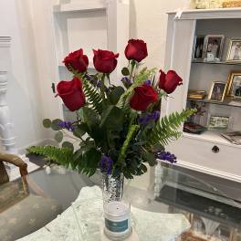 Red roses in a silver vase with purple filler flowers